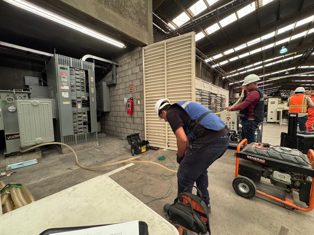 Técnicos conectando el equipo purificador de aceite a un transformador dentro de una planta