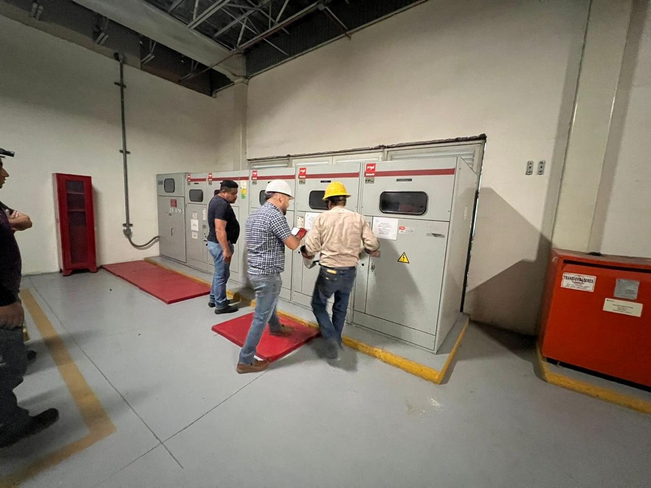 Personal técnico revisando tableros de distribución en un cuarto eléctrico